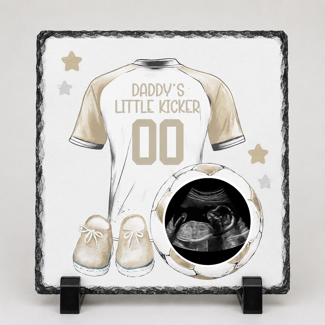 Decorative slate with a soccer jersey design, baby shoes, and ultrasound photo on a white background.