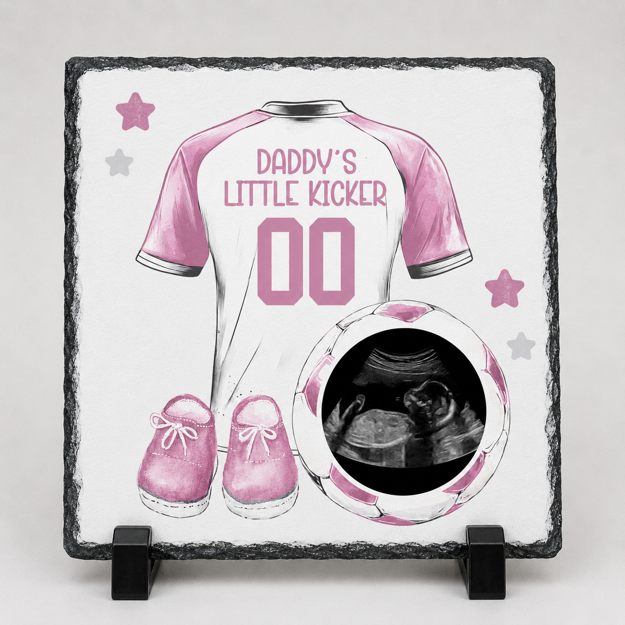 Decorative slate with pink soccer jersey, shoes, and ultrasound photo on a white background